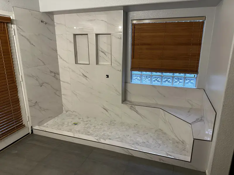 Custom marble-look tile shower with bench and recessed niches