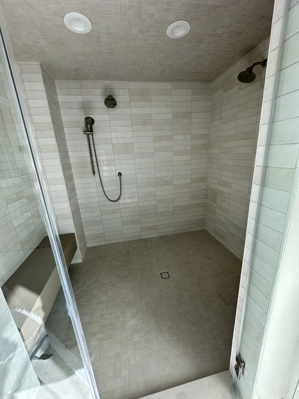 Large walk-in tile shower installation with neutral wall and floor tile